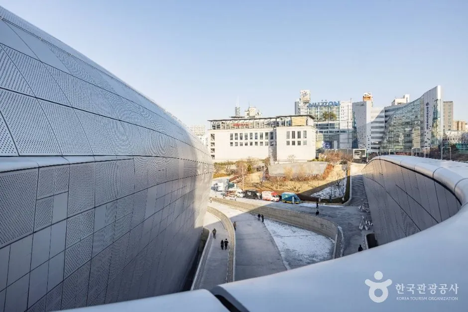 The curved metal shell of Dongdaemun Design Plaza curving away above a Seoul street