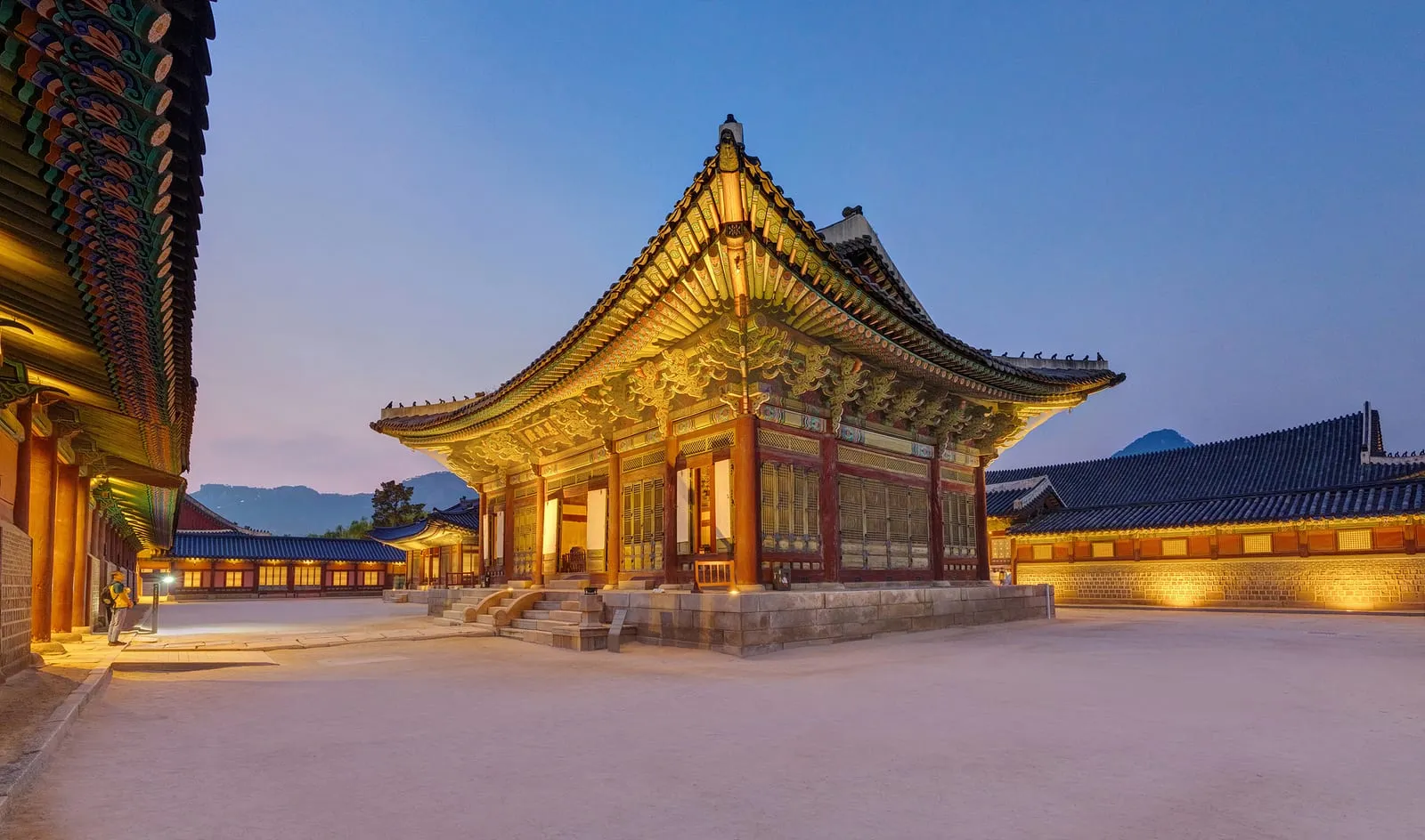 Sajeongjeon Hall at Gyeongbokgung lit at blue hour, with the palace walls behind