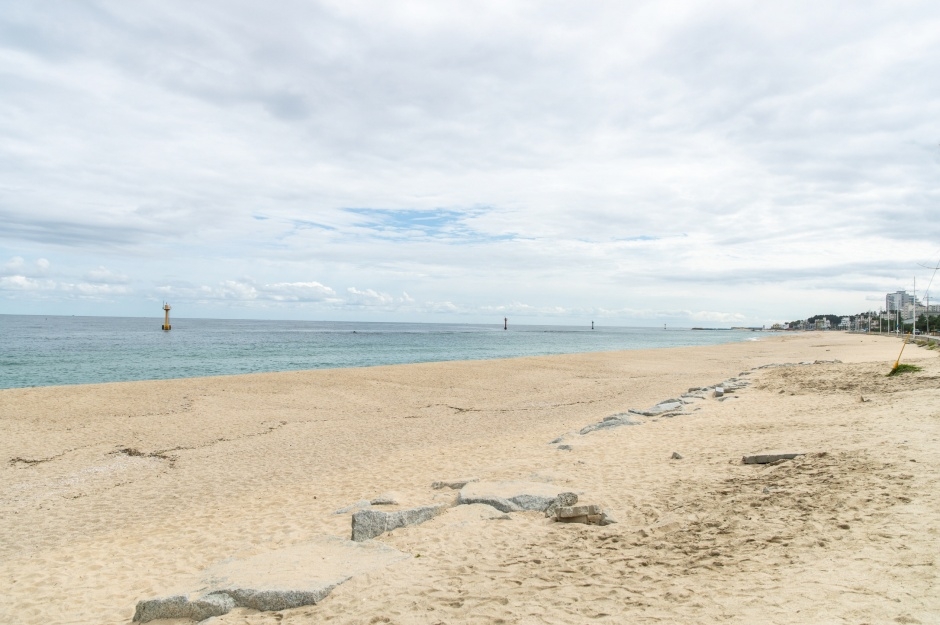A wide empty stretch of sand at Jumunjin beach on the East Sea under a bright summer sky