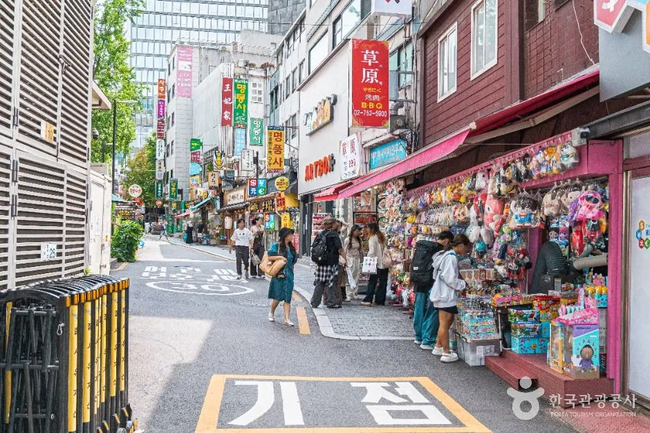 A busy Seoul shopping street in Myeongdong, shops open straight onto the pavement on both sides