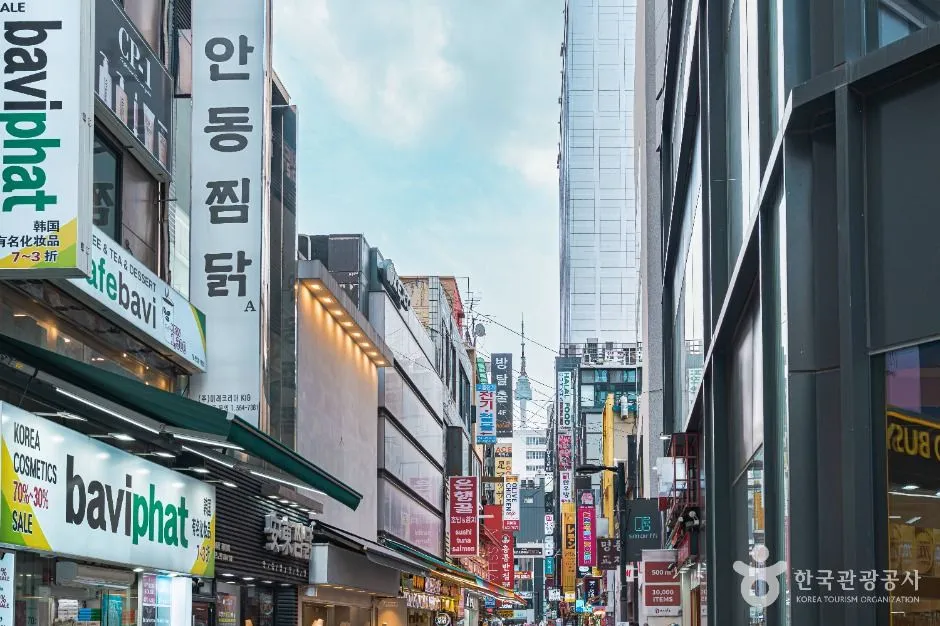 Shop signs stacked one above another up the sides of buildings on a Myeongdong street, reading upward past several floors