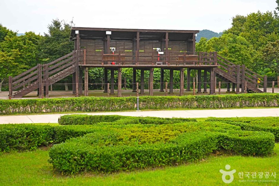A large raised wooden observation deck on stilts overlooking clipped garden beds