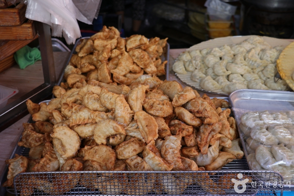 Trays of deep-fried snacks and steamed dumplings stacked at a market stall
