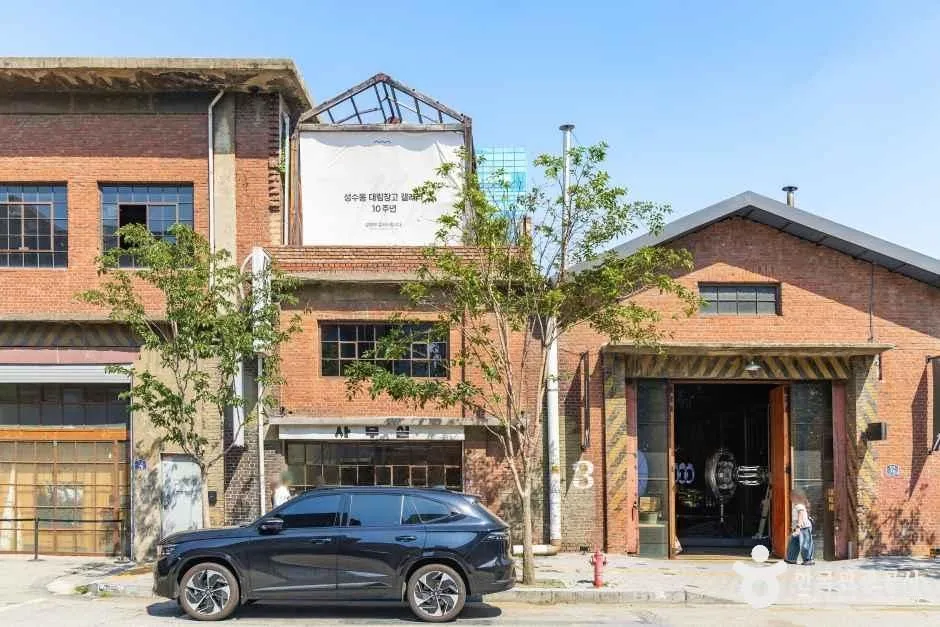 A converted red-brick industrial building in Seongsu with a rolling shutter door and a plain white sign